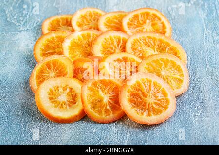 Scheiben getrockneter Orangen oder Mandarinen auf blauem Hintergrund. Vegetarismus und gesunde Ernährung. Kopierbereich Stockfoto