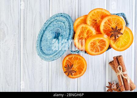 Scheiben getrockneter Orangen oder Mandarinen mit Anis und Zimt in einer blauen Schüssel auf hellem Hintergrund. Vegetarismus und gesunde Ernährung Stockfoto