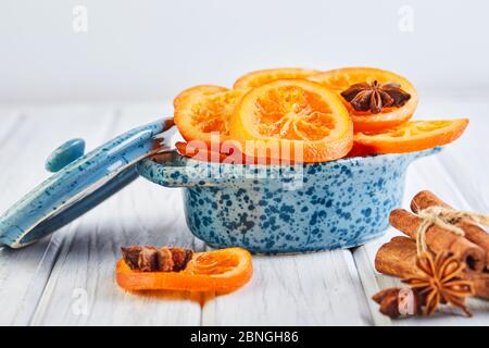 Scheiben getrockneter Orangen oder Mandarinen mit Anis und Zimt in einer blauen Schüssel auf hellem Hintergrund. Vegetarismus und gesunde Ernährung Stockfoto