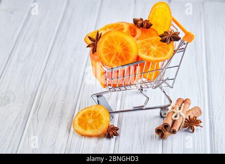 Scheiben getrockneter Orangen oder Mandarinen mit Anis und Zimt in einem Supermarkt-Wagen auf hellem Hintergrund. Vegetarismus und gesunde Ernährung. Stockfoto