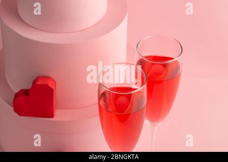 Nahaufnahme auf zwei Gläsern roten Schaumwein und Herz auf rosa Hintergrund Stockfoto
