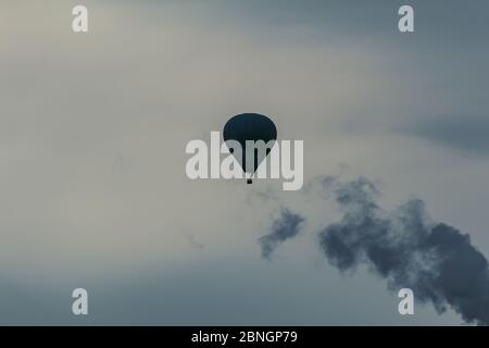 Detail der Heißluftballon fliegen am Himmel mit großem Rauch aus dem Kamin Stockfoto