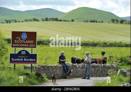 Zwei bäuerliche Nachbarn, ein Schotte (links) und der andere Engländer unterhalten sich an der England-Schottland-Grenze bei Kirk Yetholm. Stockfoto