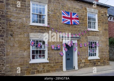 Steinhaus, dekoriert mit Union Jack Funting für VE Day 75. Jahrestag Feiern, Little Houghton, Northamptonshire, Großbritannien Stockfoto