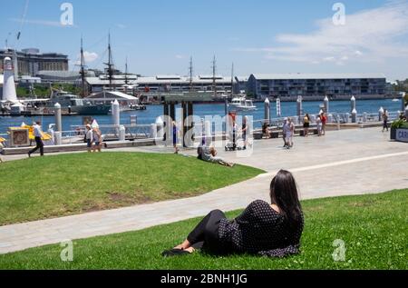 Junge Frau, die sich auf dem Rasen im Darling Harbour, Sydney, Australien, entspannt. Stockfoto