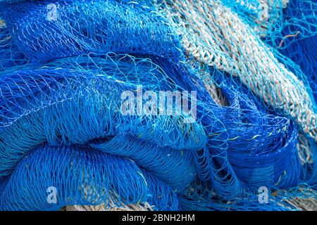 Blick von oben auf blaue Fischernetze, die im Sonnenschein liegen und den gesamten Rahmen des Schusses füllen. Stockfoto