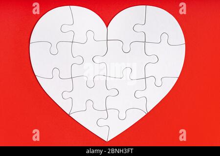 Puzzle-Teile in Form von Herz auf rotem Hintergrund. Liebe, Nächstenliebe, Spende, helfende Konzept. Perfekt abgestimmt, Wiedersehen. Stockfoto
