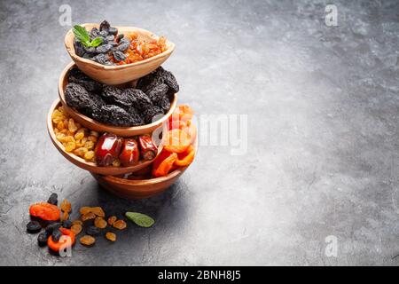 Verschiedene getrocknete Früchte und Nüsse auf einem dunklen Steintisch. Mit Kopierbereich Stockfoto