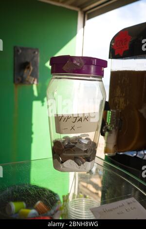 Nahaufnahme eines Glas-Tipp-Glas mit Münzen auf der Theke einer Snack-Bar am Strand in der Nähe von Lyme Regis, Großbritannien Stockfoto