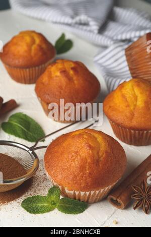 Komposition mit Muffins und Zimt auf weißem Hintergrund Stockfoto