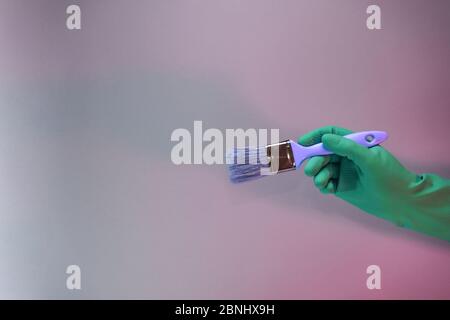 Schöne Hand hält Pinsel in der Neonlicht. Minimalistisches Retro-Konzept. Hintergrundmuster für Design. Stockfoto