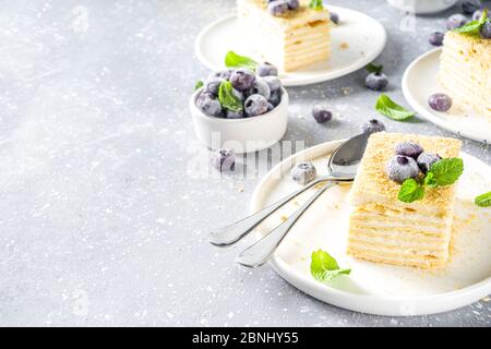 Hausgemachte Kuchen Napoleon, Millefeuille. Delikater Pudding-Kuchen, garniert mit Beeren und Minze. Auf einem grauen Betonstein Hintergrund. Stockfoto