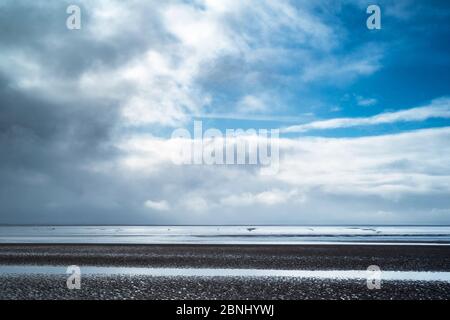 Das Meer und der Sandstrand sind in Pastelltönen gehalten und liegen unter dem kristallblauen Himmel des Bristol Channel an der Küste von Burnham-on-Sea, Somerset, Großbritannien Stockfoto