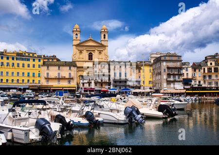 Sehen Sie sich die église Saint Jean-Baptiste in Bastia vom vieux Hafen aus an, während der Sommermonate einige Boote im Hafen ruhen Stockfoto