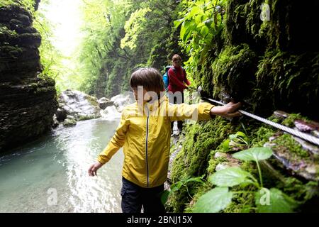 Mutter und Sohn gehen durch die Flussschlucht mit einem Sicherheitseil zum Kozjak Wasserfall, Slowenien Stockfoto