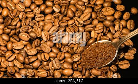 Kaffeebohnen Nahaufnahme mit einem Löffel gemahlenen Kaffee auf einem spiegelnden Hintergrund. Stockfoto