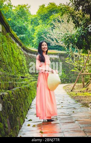 Eine junge Vietnamesin in einem Ao Dai Kleid und konischem Hut in einem buddhistischen Tempel, Hue, Vietnam, Indochina, Südostasien, Asien Stockfoto