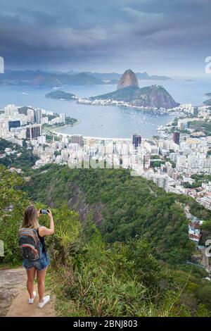 Eine Wanderin mit Blick auf die Landschaft von Rio zum Zuckerhut Berg vom Tijuca Nationalpark, Rio de Janeiro, Brasilien, Südamerika