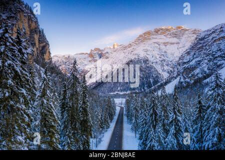 Luftaufnahme per Drohne des Sonnenaufgangs auf der Panoramastraße Toblach-Misurina entlang verschneiten Wäldern, Dolomiten, Südtirol, Italien, Europa Stockfoto