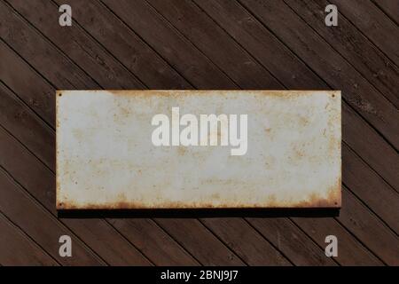 Altes Zinnschild für Textvorlage an einer alten Holzwand. Stockfoto