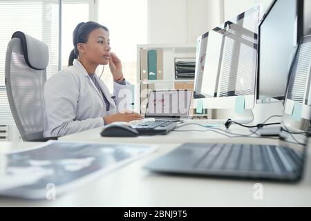 Seriöse Ärztin in Kopfhörer Blick auf Computer-Monitor hat sie Online-Konferenz im Büro Stockfoto
