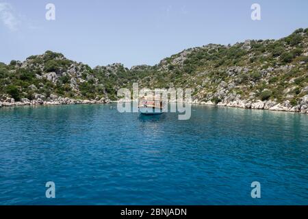 Kalekoy, Demre, Türkei - 03. Juni 2019: Badetouristen in der Nähe der Vergnügungsyacht. Die felsige Küste der Insel Kekova im Mittelmeer Stockfoto