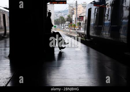 Passagiere, die auf den Bahnhof warten. Silhouette Menschen am Bahnhof, im Hintergrund die Stadt Valparaiso, Chile Stockfoto