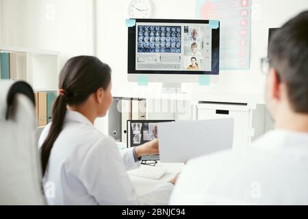 Eine Gruppe von Ärzten auf einem Computermonitor, die während einer Online-Konferenz Röntgenbilder mit Kollegen diskutieren Stockfoto