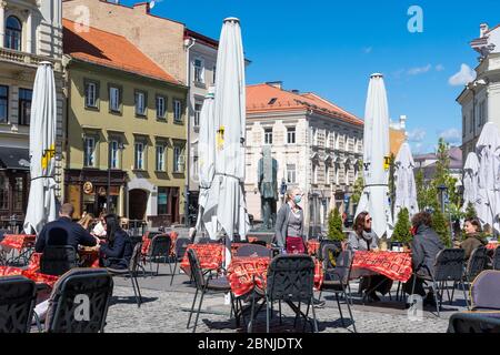 Bar und Restaurant mit Kunden und Kellnerin mit Maske und Handschuh in Vilnius, litauische Hauptstadt, die in eine große Open-Air-Café-Stadt verwandelt werden wieder eröffnet Stockfoto