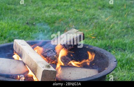 Ein knisterndes Feuer bricht sanft mit Funken aus einer bescheidenen Feuergrube Stockfoto