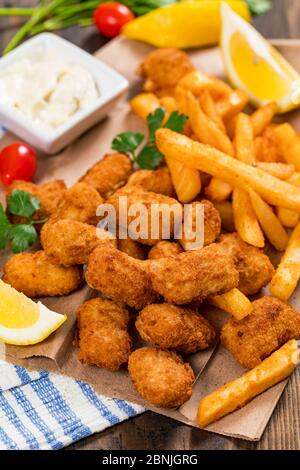 Knusprige Fischbites Snack Größe. Tiefgebratene Pollock Fischfinger mit Tartar-Bratsauce auf Holzbrett Stockfoto