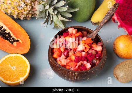 Tropischer Obstsalat in Kokosnussschale auf hellblauem Hintergrund, Horizontal Format Stockfoto