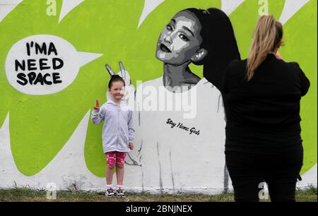 Michelle Lyons fotografiert ihre Tochter Lauren Ryan (5) mit der irischen Künstlerin Emmalene Blake auf dem Wandgemälde von Ariana Grande in Süd-Dublin. Dies ist das jüngste in der Serie 'Stay at Home' des Dubliner Künstlers, der die Menschen dazu ermutigt, sich an soziale Distanzierungen zu halten. Weitere Künstler waren Dua Lipa, Tia und Tamera Mowry, Cardi B, Robyn, The Police, Ice Cube, Pinky and the Brain und David Bowie. Siehe PA Geschichte GESUNDHEIT Coronavirus Irland. Das Foto sollte lauten: Brian Lawless/PA Wire Stockfoto