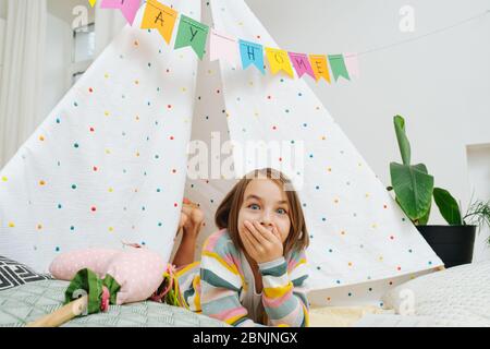 Schockierte Mädchen lesen vor einer Hütte mit Aufenthalt zu Hause Flagge Girlande gegenüber Stockfoto