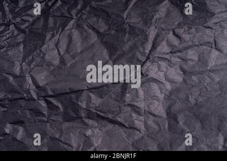 Dunkle zerknitterte gefaltet schwarzen Papier Poster Textur. Unbeschriftete zerknitterte, körnige Papieroberfläche. Verschmierter, munziger Karton mit Faser. Nahaufnahme. Stockfoto