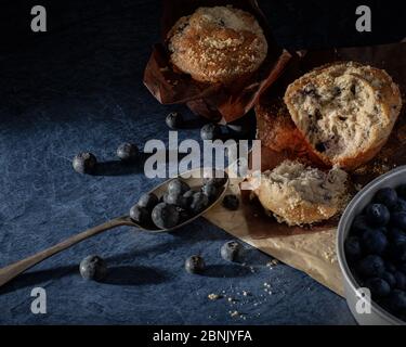 Heidelbeer-Muffins und frische Heidelbeeren auf einer Schieferarbeitsfläche Stockfoto