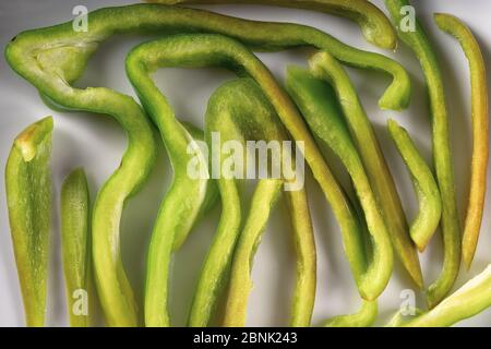 Grüne Paprika Scheibe oder Schnitt Textur. Kreative Gestaltung der Pfefferstücke. Set von geschnittenem Gemüse auf weißem Teller. Food Art. Abstrakt minimal kompostiert Stockfoto
