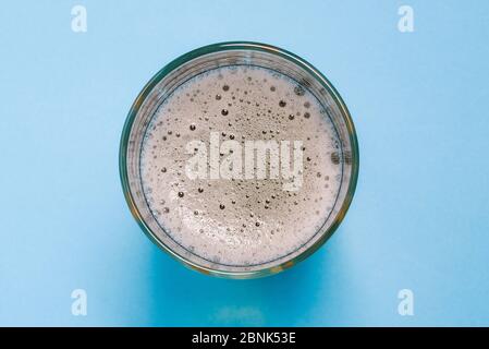 Glas mit Bier auf blauem Hintergrund. Kaltes alkoholisches Getränk. Eine Draufsicht eines flachen Layouts. Stockfoto