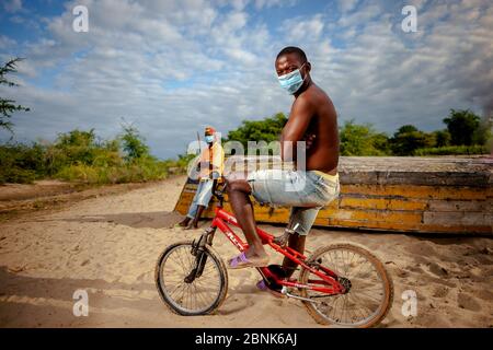 Bild eines Mannes mit Maske auf einem Fahrrad in Malawi Stockfoto