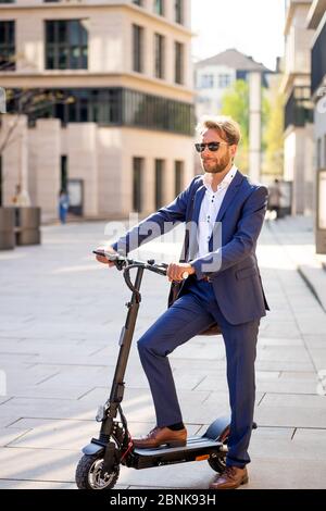 Mann im Anzug auf einem E-Scooter Stockfoto