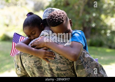 Afroamerikanischer Mann in Militäruniform, der seine Kinder hält Stockfoto