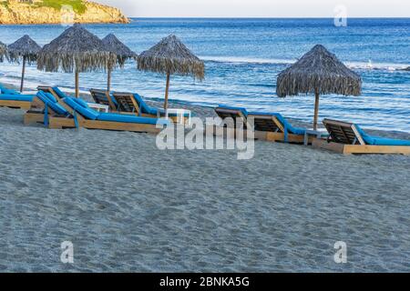 Leere luxuriöse Holzliegen mit blauer Matratze und Bambus Sonnenschirmen am Sandstrand von Mykonos, Griechenland Paradise Beach. Stockfoto