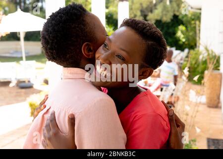 Ältere afroamerikanische Frau umarmen mit ihrer Tochter während eines Familienmittagessen im Garten Stockfoto