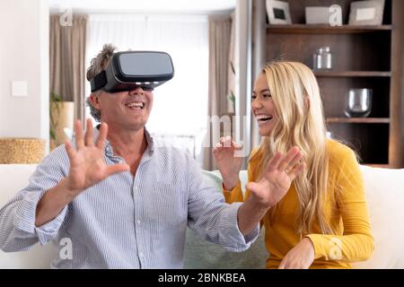 Ein älterer kaukasischer Mann und seine Erwachsene Tochter verwenden zu Hause ein VR-Headset Stockfoto