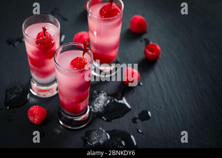 Raspberry Vodka Shots Cocktail mit frischer Himbeere auf schwarzem Hintergrund Stockfoto