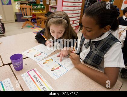 Austin Texas, USA, Januar 2013: Schwarze und weiße Klassenkameradin in Uniformen arbeiten gemeinsam an der Klassenarbeit in der zweiten Klasse der katholischen Privatschule. ©Bob Daemmrich Stockfoto