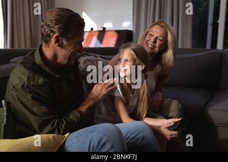 Porträt eines kaukasischen Mädchens und ihrer Großeltern auf einer Couch sitzend Stockfoto
