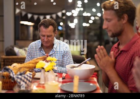MehrgenerationenFamilie Kaukasisch beten vor dem Essen Stockfoto