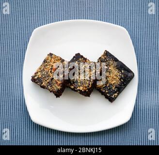 BROWNIES IN EINEM WEISSEN TELLER, GARNIERT MIT GERÖSTETEN MANDELN Stockfoto