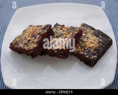 BROWNIES IN EINEM WEISSEN TELLER, GARNIERT MIT GERÖSTETEN MANDELN Stockfoto